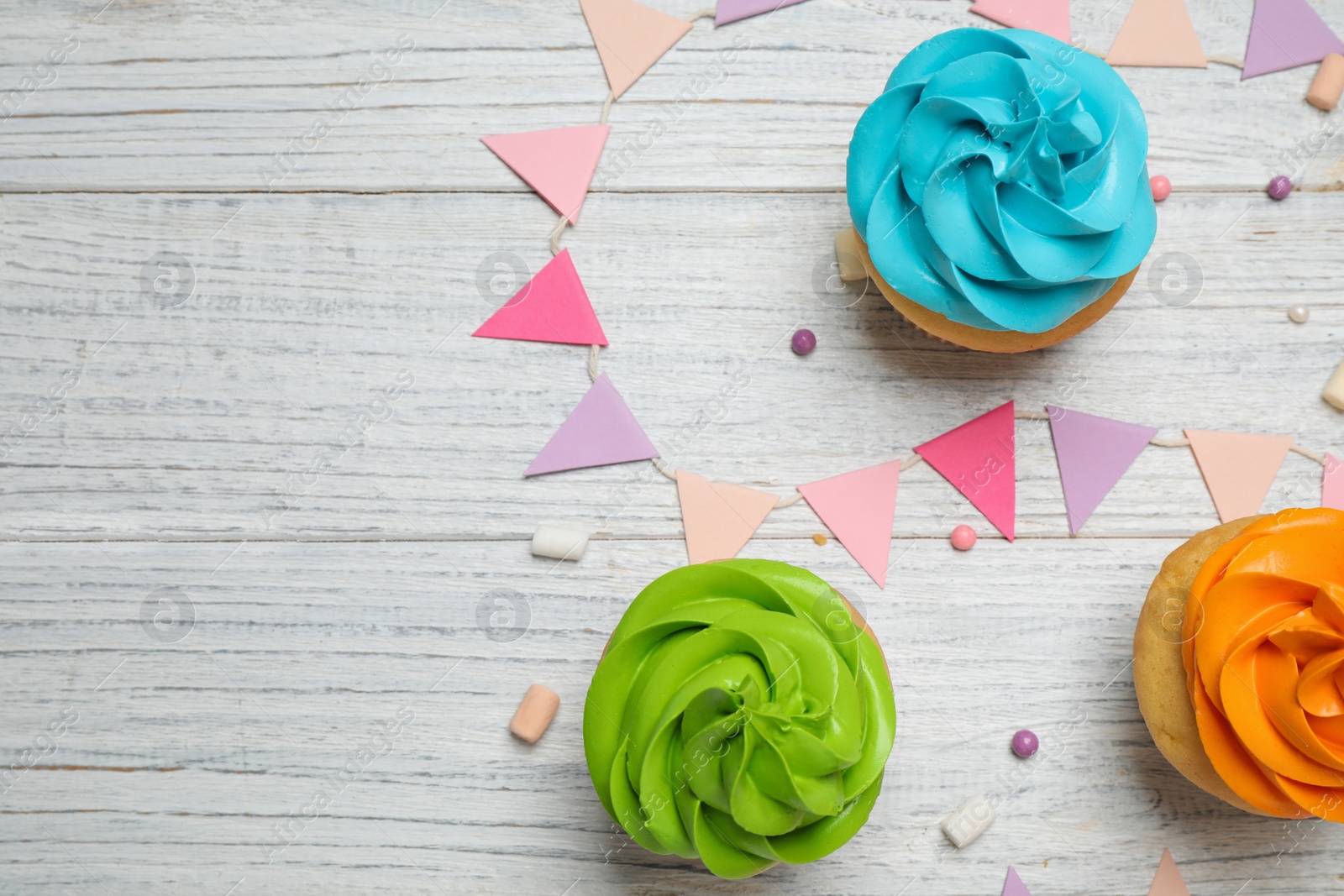 Photo of Colorful birthday cupcakes on white wooden table, flat lay. Space for text