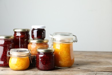 Photo of Jars with different jams on wooden table