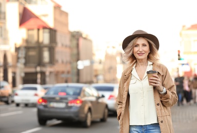 Photo of Mature woman with cup of coffee on city street
