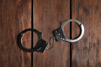 Classic chain handcuffs on wooden table, top view