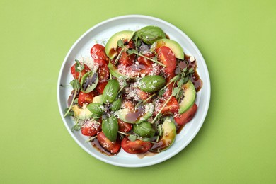 Photo of Tasty salad with balsamic vinegar on light green background, top view