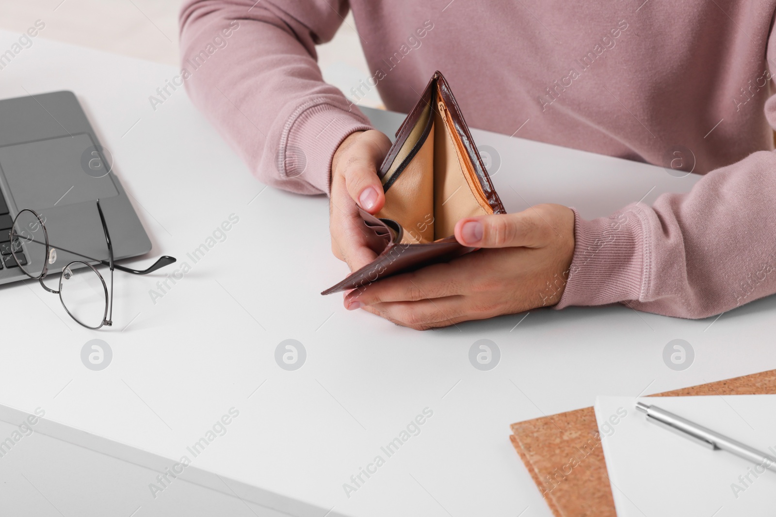 Photo of Man with empty wallet at white table indoors, closeup