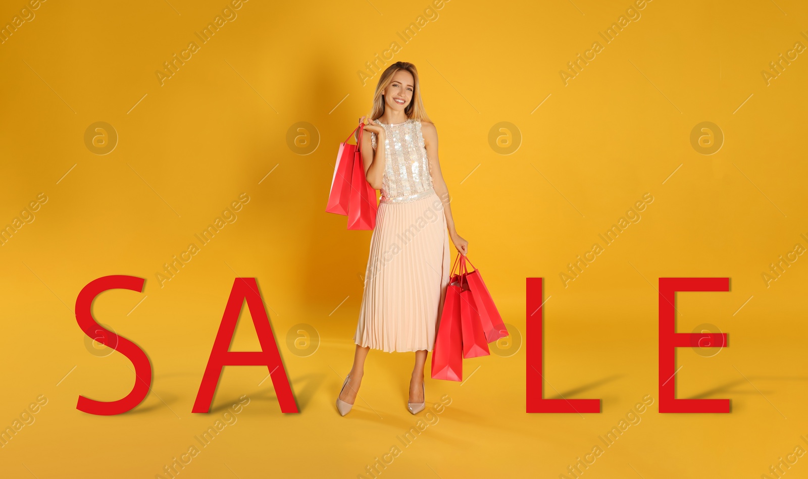 Image of Happy young woman with shopping bags and word SALE on yellow background