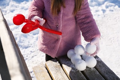 Photo of Little girl playing with snowball maker outdoors, closeup