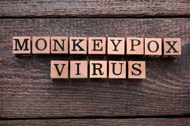 Photo of Words Monkeypox Virus made of cubes on wooden table, flat lay
