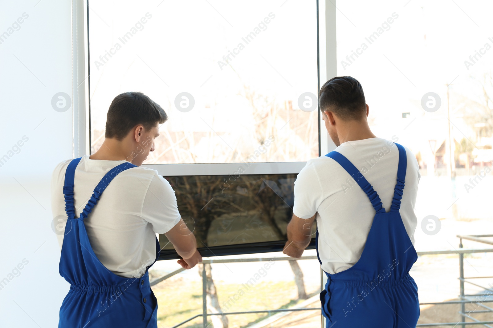 Photo of Professional workers tinting window with foil indoors