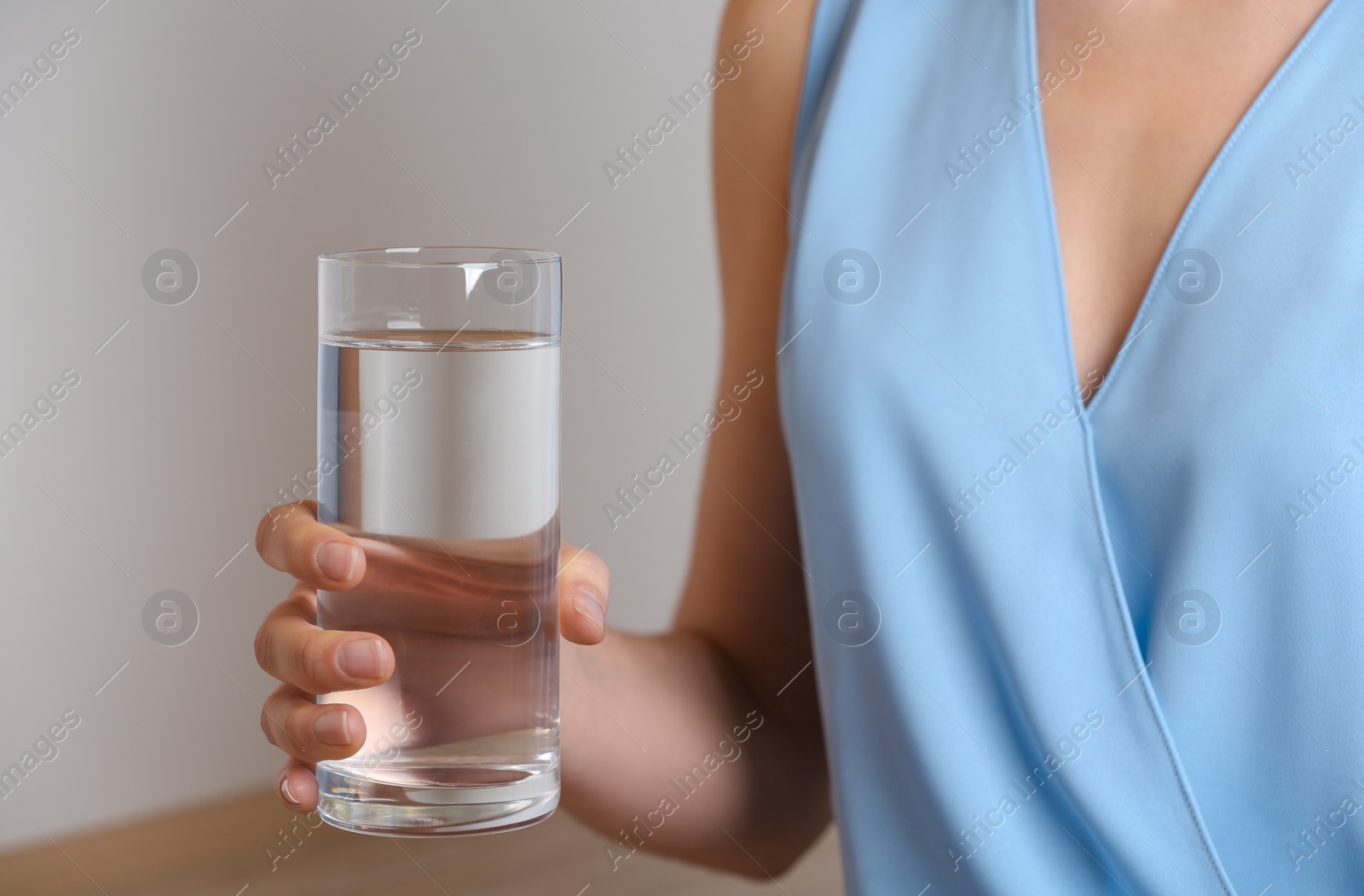 Photo of Woman holding glass with fresh water indoors, closeup