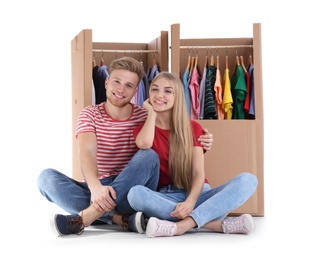 Young couple near wardrobe boxes on white background