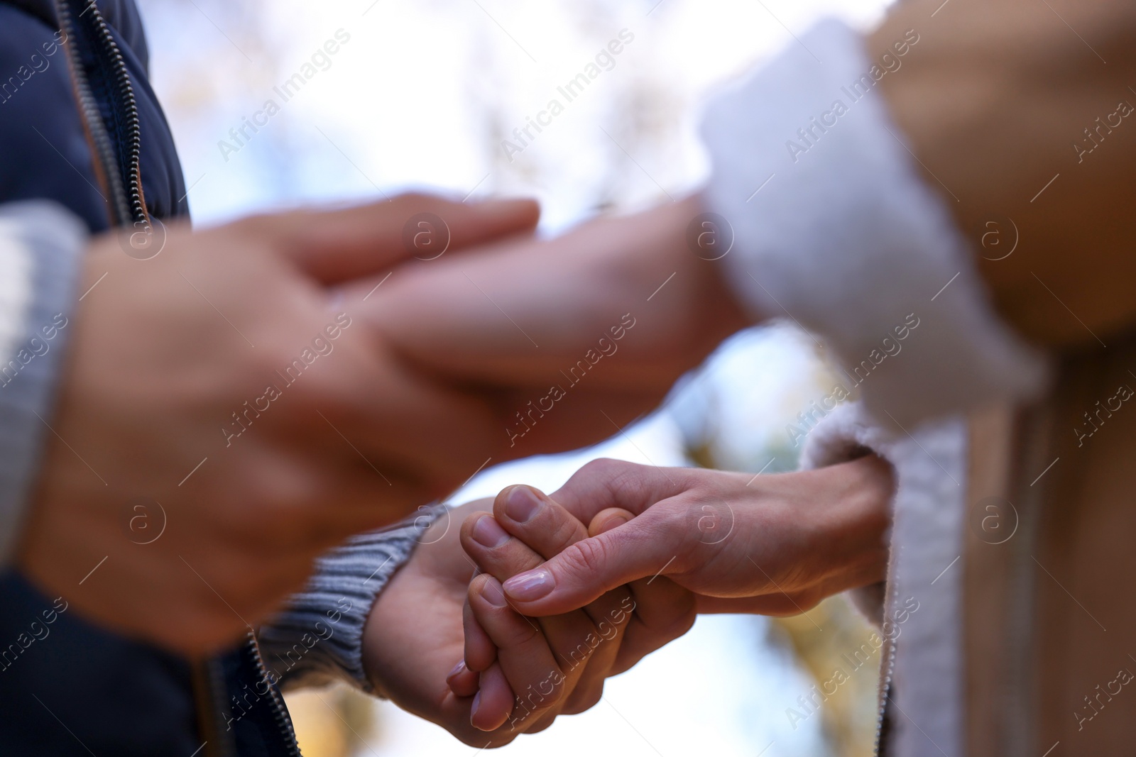 Photo of Happy young couple holding hands together outdoors, closeup. Dating agency