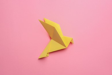 Photo of Beautiful yellow origami bird on pink background, top view