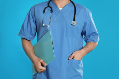 Photo of Doctor with clipboard on blue background, closeup