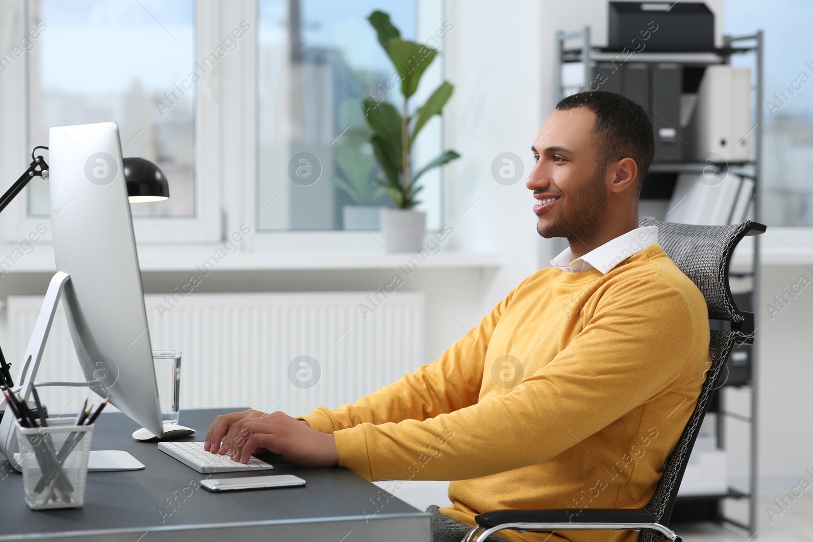 Photo of Young man working on computer at table in office