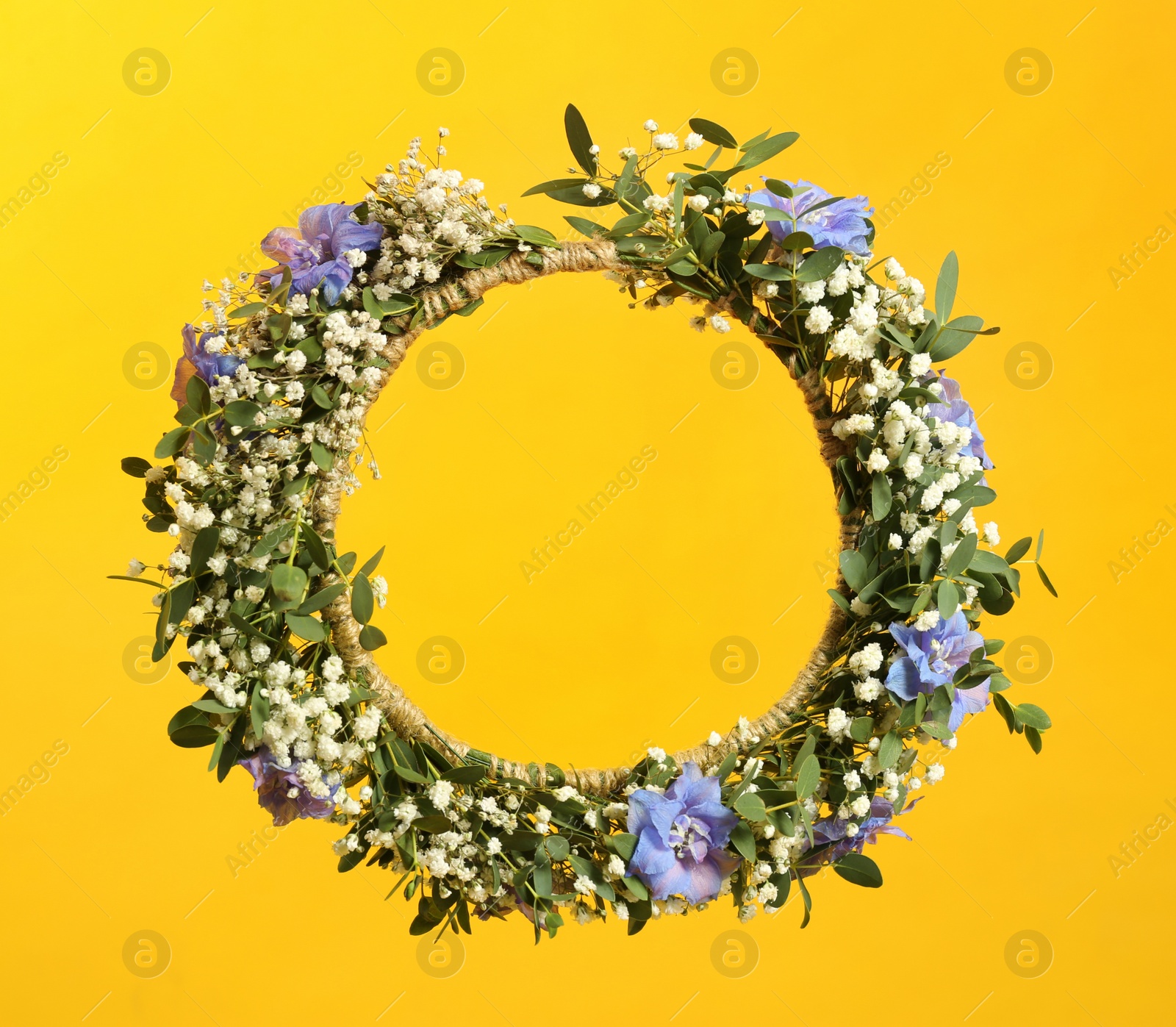 Photo of Beautiful handmade flower wreath on yellow background