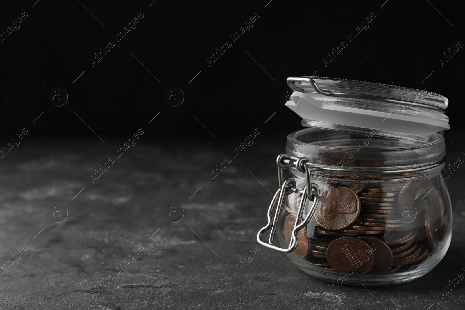 Photo of Glass jar with coins on grey table, space for text