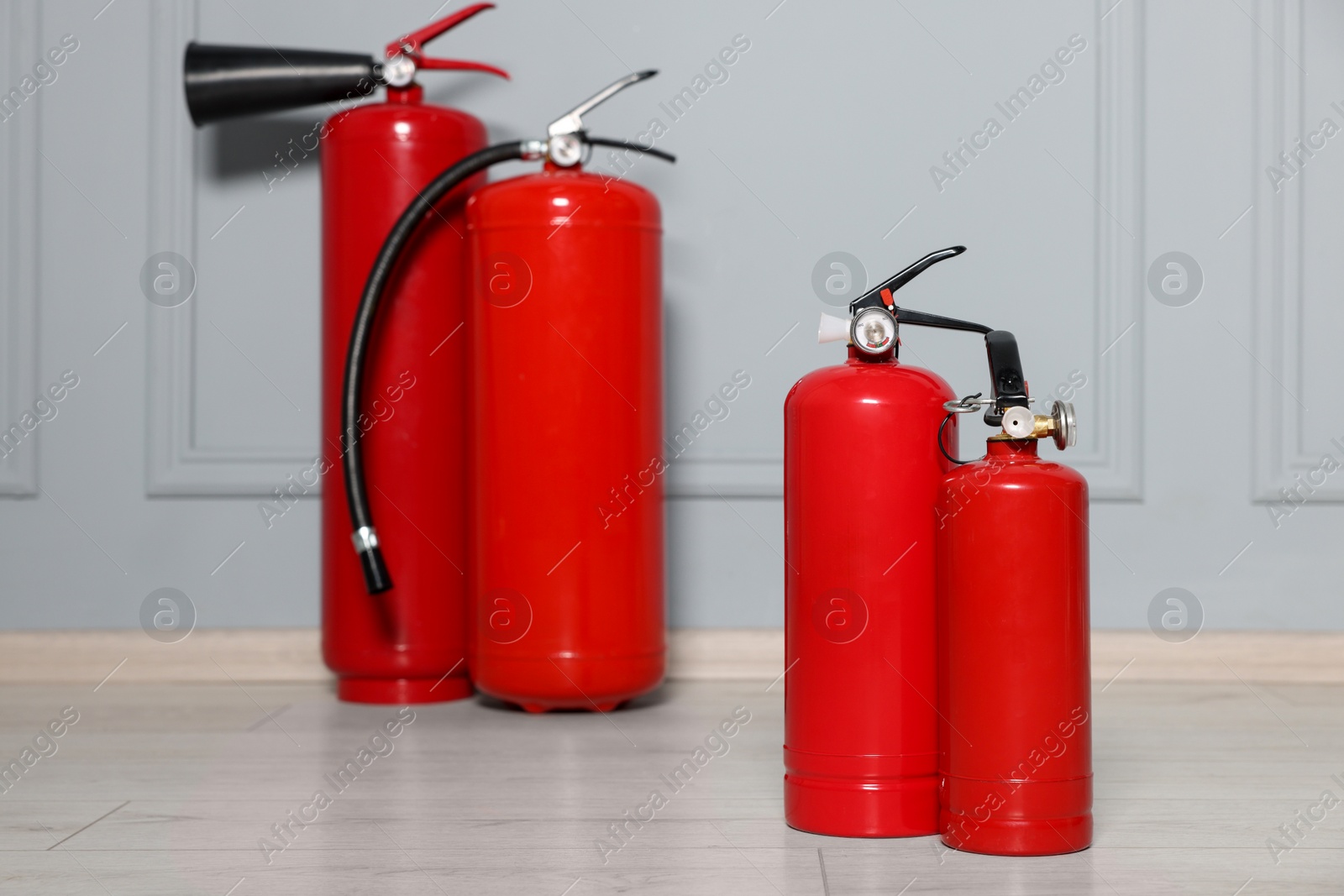 Photo of Red fire extinguishers near grey wall, selective focus