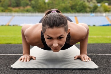 Photo of Young woman doing plank exercise at stadium
