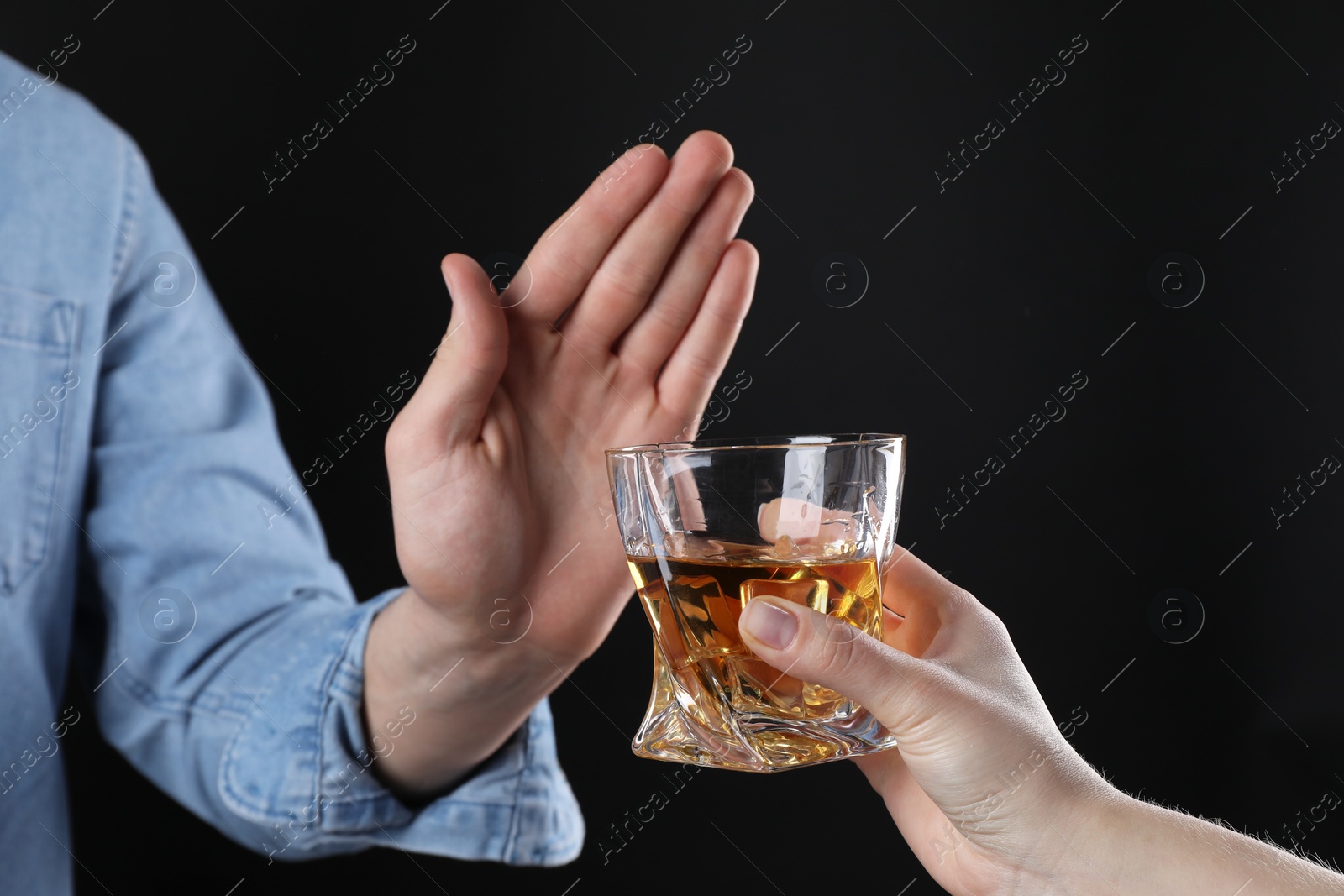 Photo of Alcohol addiction. Man refusing glass of whiskey on dark background, closeup