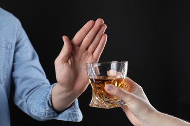 Photo of Alcohol addiction. Man refusing glass of whiskey on dark background, closeup