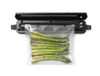 Photo of Sealer for vacuum packing with plastic bag of asparagus on white background, top view