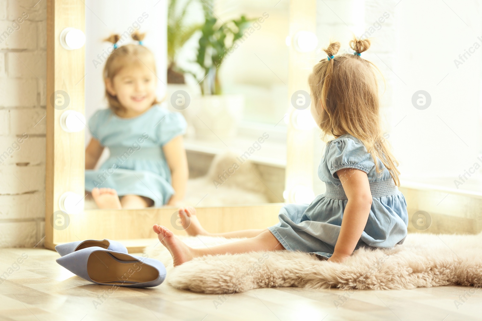 Photo of Cute little girl sitting on floor at home