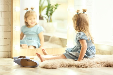 Cute little girl sitting on floor at home