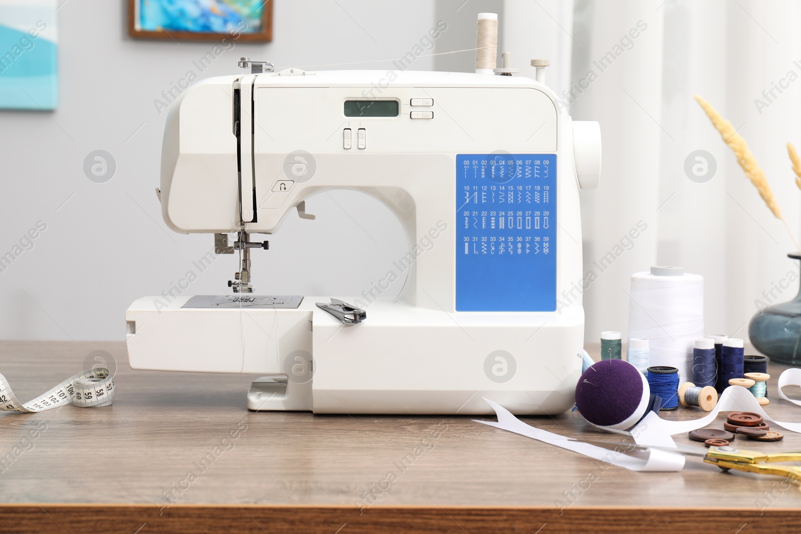 Photo of White sewing machine and craft accessories on wooden table indoors