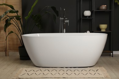 Photo of Spa day. Stylish bathroom with ceramic tub and houseplants