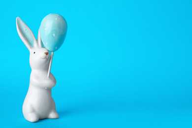 Photo of Bunny ceramic figure as Easter decor on blue background. Space for text