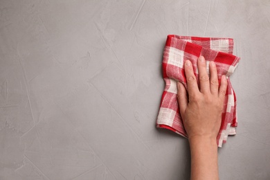 Photo of Woman wiping stone surface with kitchen towel, top view. Space for text