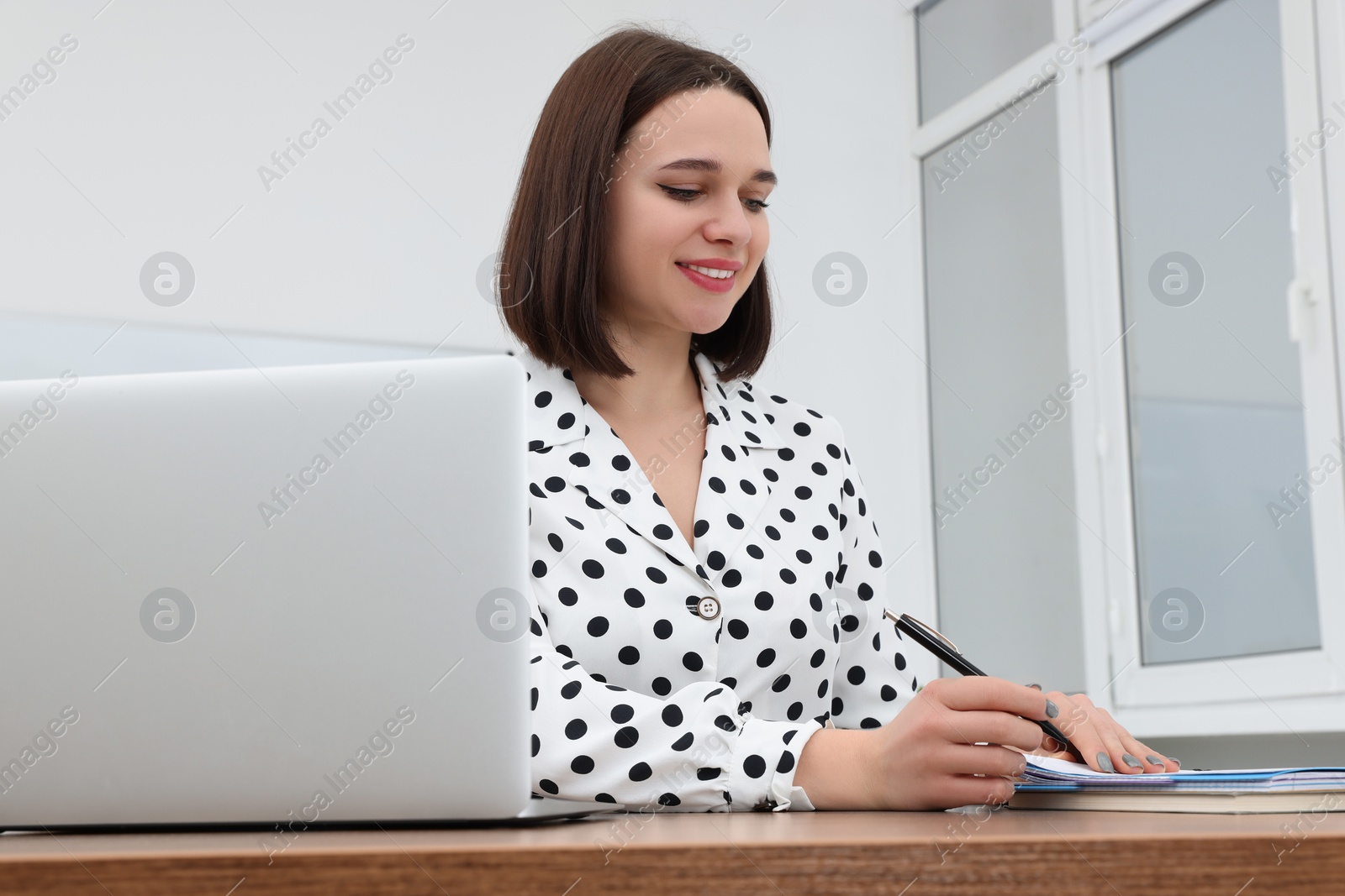 Photo of Happy young intern working at table in modern office