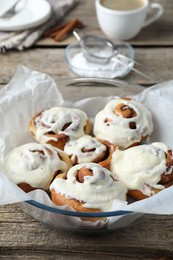 Tasty cinnamon rolls with cream on wooden table, closeup