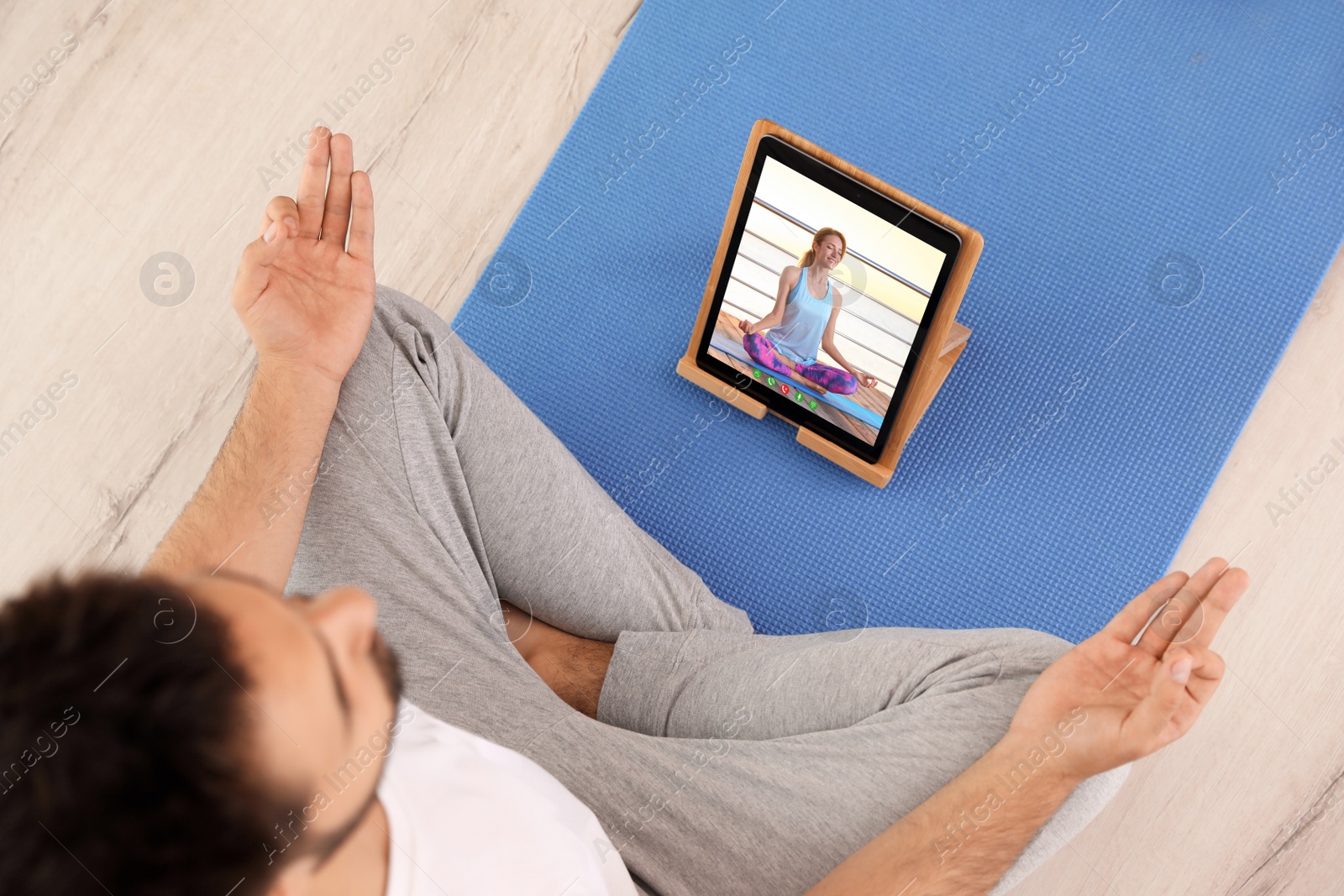 Image of Distance yoga course during coronavirus pandemic. Man having online practice with teacher via tablet at home, above view