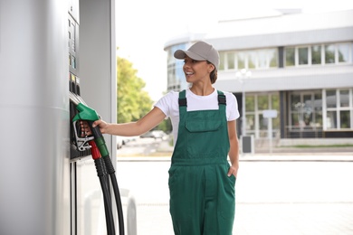 Photo of Worker taking fuel pump nozzle at modern gas station