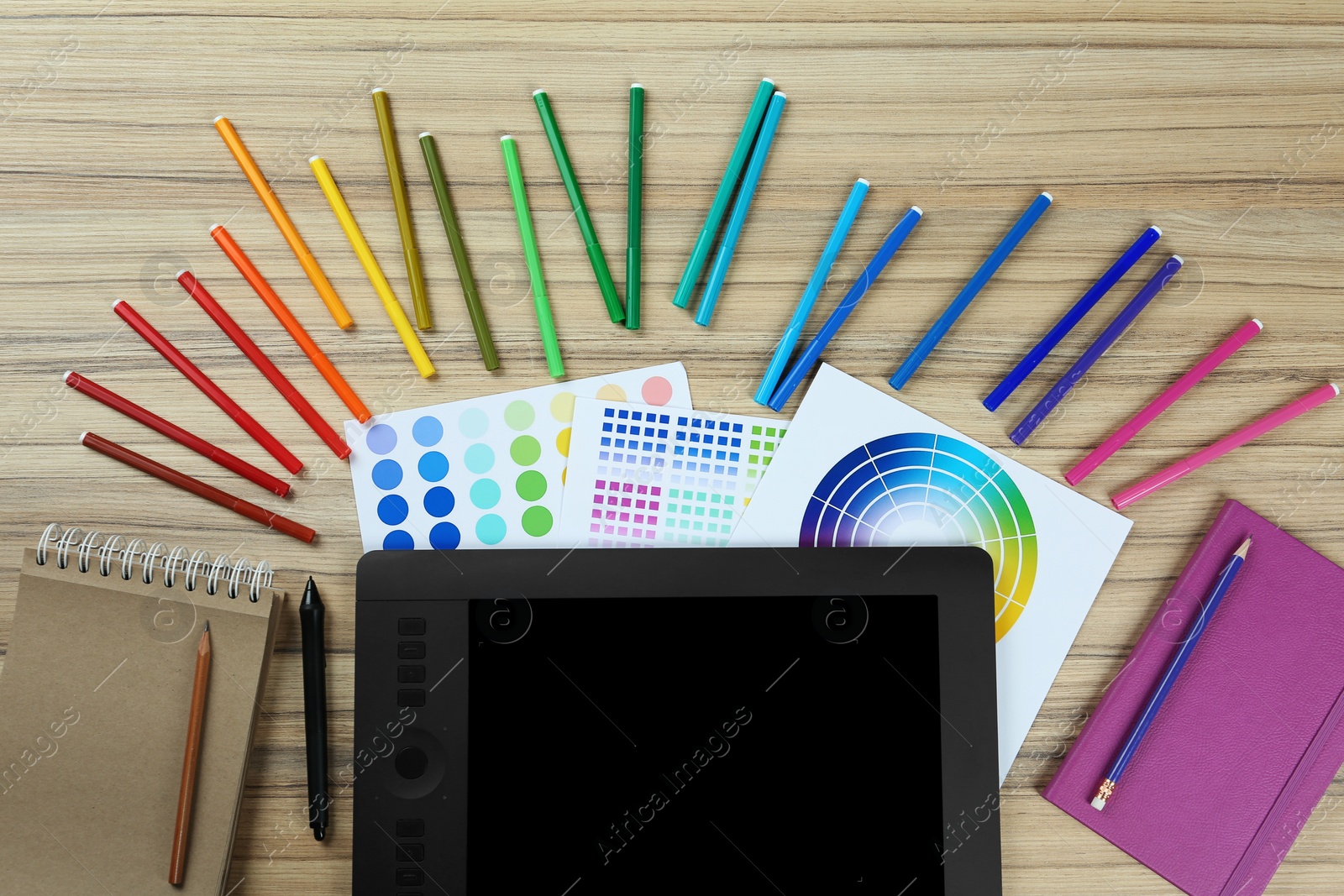 Photo of Flat lay composition with graphic tablet, color palettes and markers on wooden background, space for text. Designer's workplace