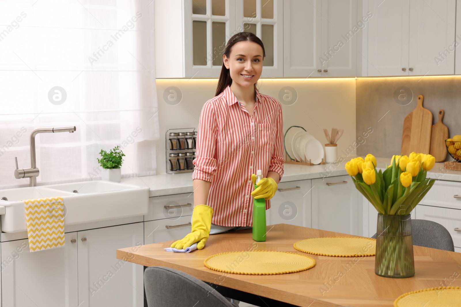 Photo of Spring cleaning. Young woman tidying up kitchen at home