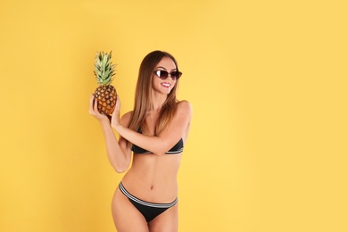 Photo of Pretty sexy woman in stylish bikini with pineapple on color background
