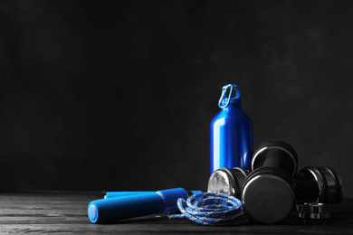 Photo of Gym equipment and accessories on floor against dark background. Space for text