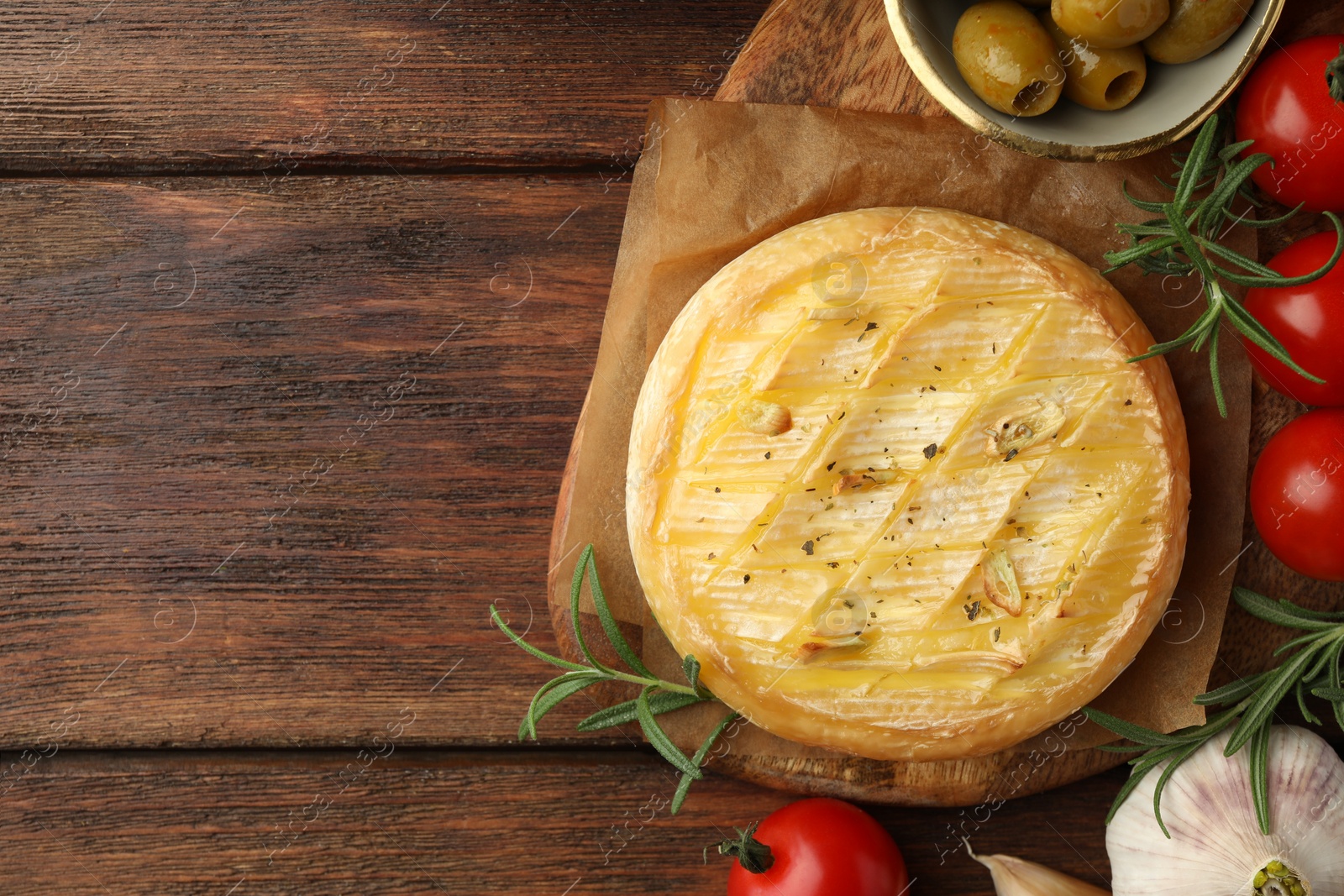 Photo of Tasty baked brie cheese served on wooden table, flat lay. Space for text