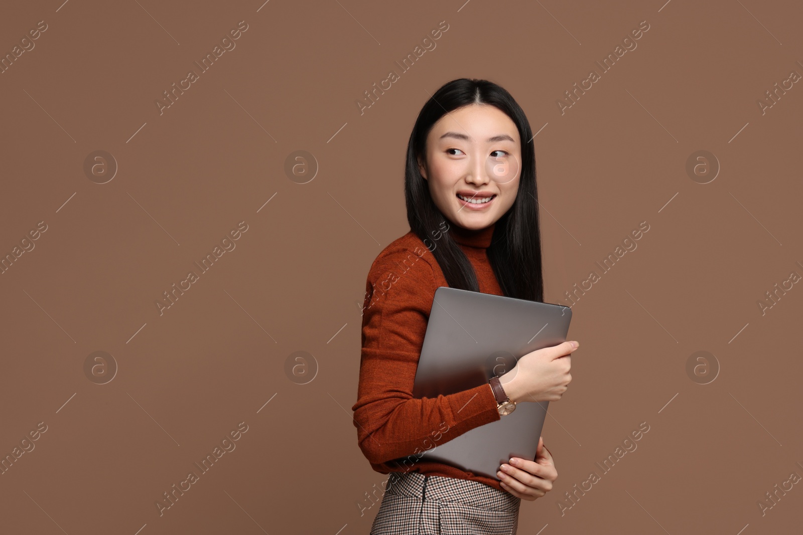 Photo of Portrait of smiling woman with laptop on brown background. Space for text