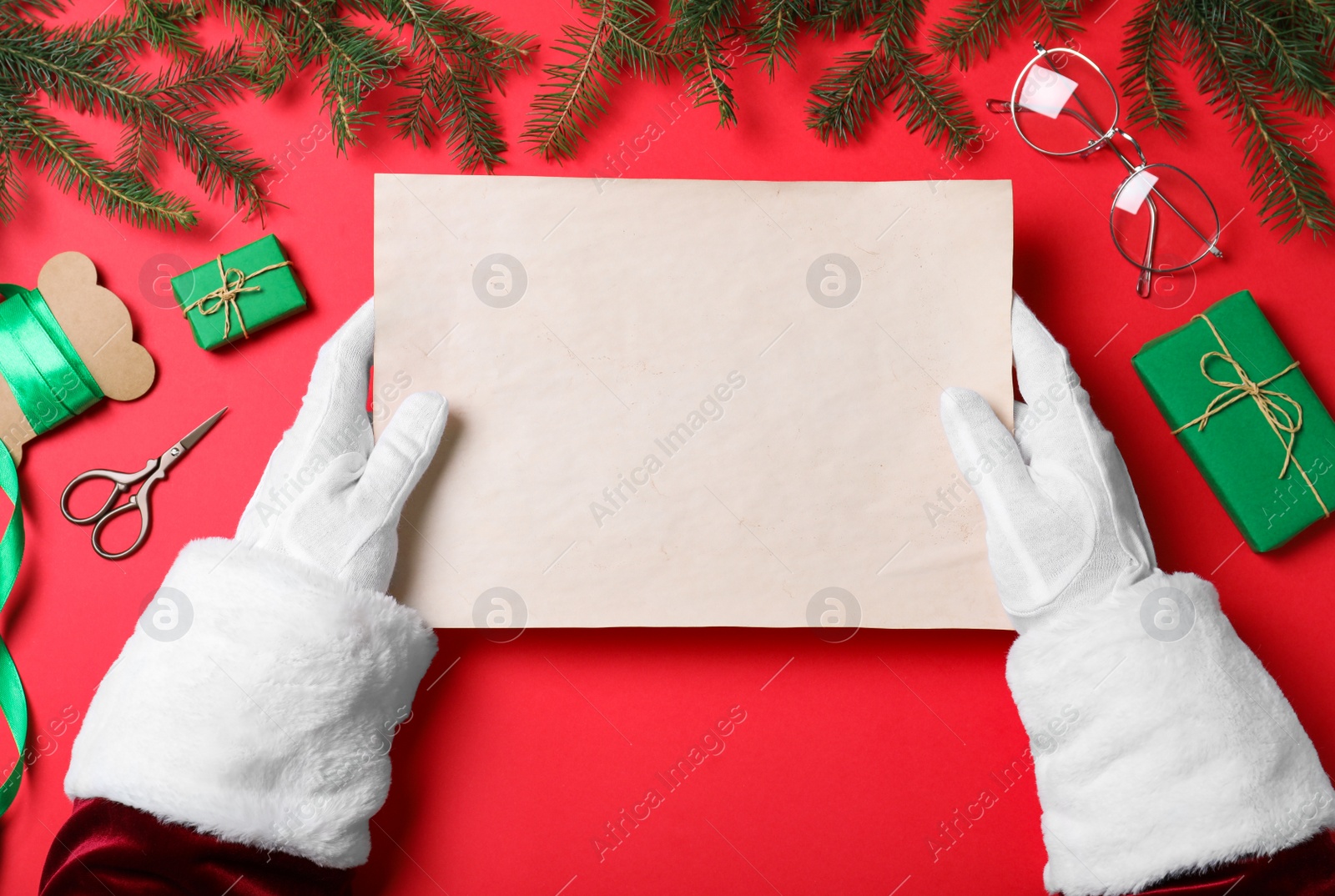 Photo of Santa Claus holding empty paper on red background, top view. Space for text