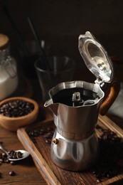 Brewed coffee in moka pot and beans on wooden table