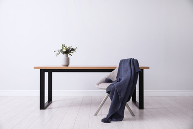 Photo of Table and chair near white wall in room. Stylish interior design