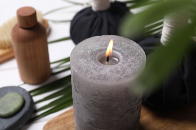 Photo of Beautiful composition with burning candle and spa products on white table, closeup