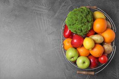 Basket with ripe fruits and vegetables on grey table, top view. Space for text