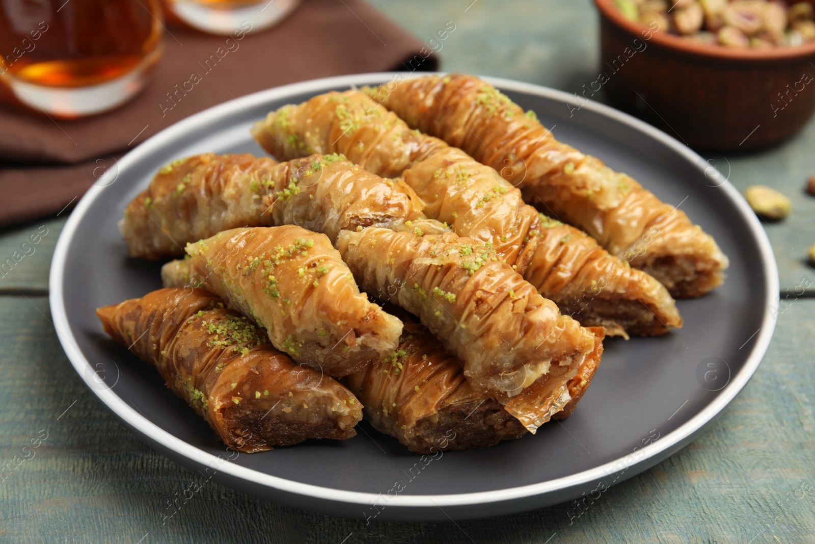 Photo of Delicious baklava with pistachios on light blue wooden table, closeup