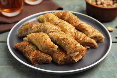 Delicious baklava with pistachios on light blue wooden table, closeup