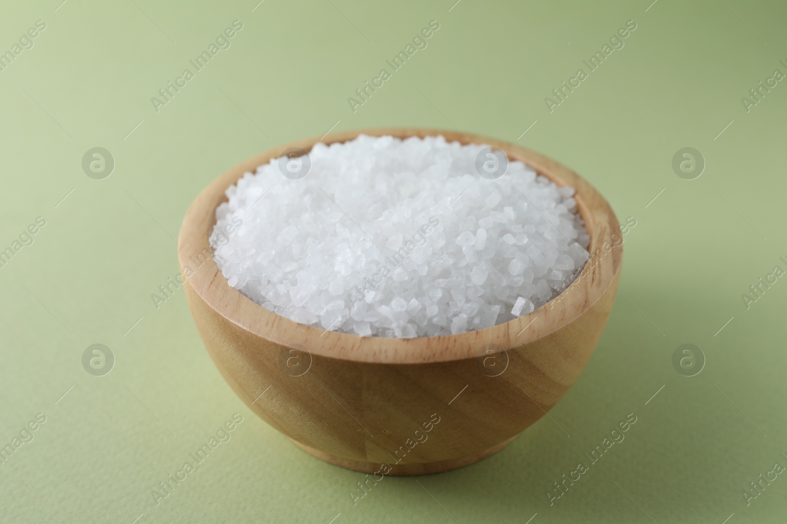 Photo of Organic white salt in bowl on olive background, closeup