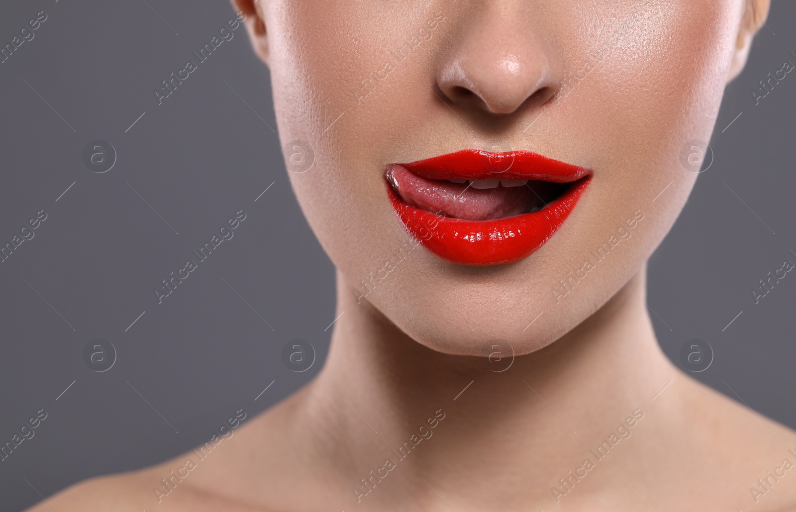 Photo of Young woman with red lips makeup on grey background, closeup. Space for text