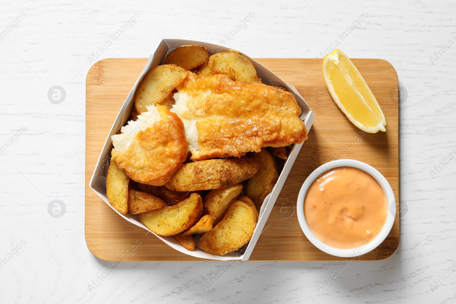 Photo of Disposable container with British Traditional Fish and potato chips on wooden background, top view