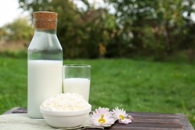 Photo of Tasty fresh milk and cottage cheese on wooden table outdoors. Space for text